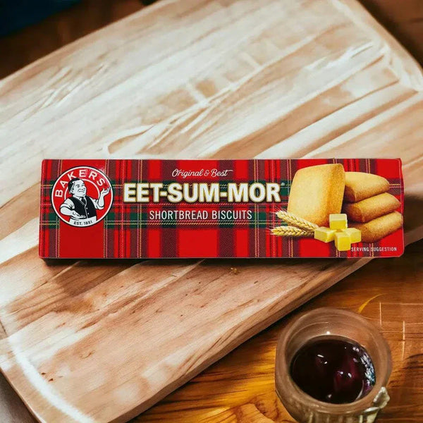 Bakers Eet-Sum-Mor shortbread biscuits in red packaging on a wooden cutting board with a cup of tea