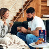 Two people enjoying Bakers Romany Classic Choc Coconut Flavour Rusks with coffee in a cozy setting.