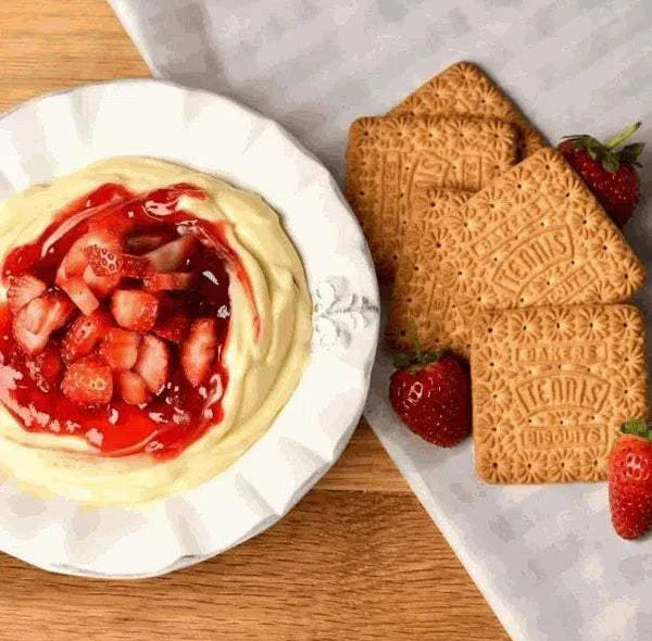 Bakers Tennis Biscuits with strawberries and cream dessert on a wooden table.