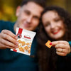 Bakers Tennis Mini Classic Coconut Biscuits pack held by two people, showing biscuit piece and packaging.