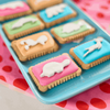 Bakers Zoo Biscuits on a tray with iced animal shapes on colorful backgrounds.