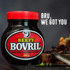 Jar of Beefy Bovril meat and vegetable extract with a red lid on a dark surface with text "BRU, WE GOT YOU" in the background