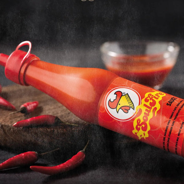Chicken Licken Soulfire Hot Sauce 100ml bottle with red chili peppers and sauce bowl, spicy South African flavor