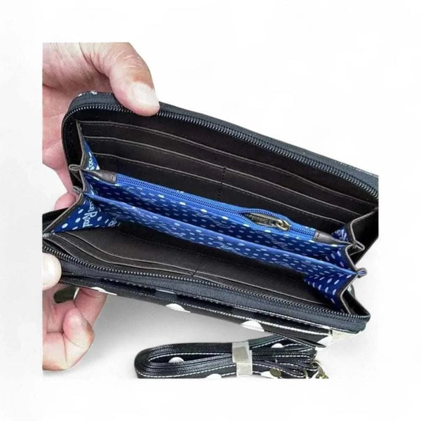 Black sling wallet with large white dots, removable shoulder strap, zip and clip compartments, blue polka dot interior lining.