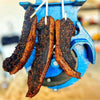 dried chilli bite biltong strips hanging on a blue biltong slicer machine showcasing spicy seasoning