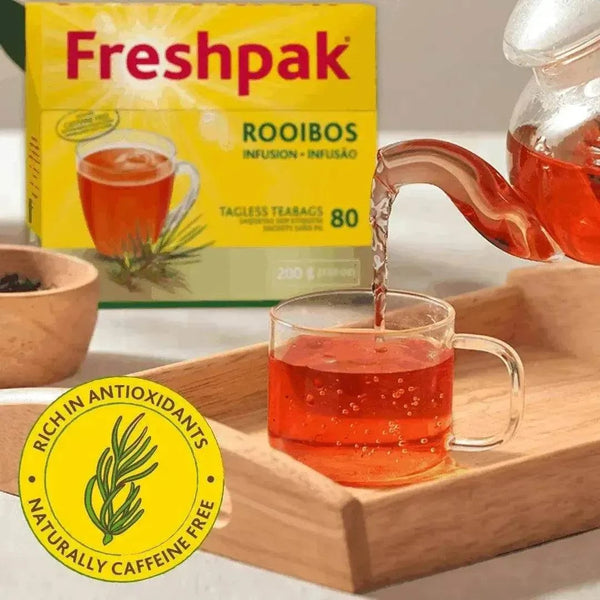 Freshpak Rooibos Tea 80's box with tea being poured into a clear glass cup on a wooden tray, highlighting natural caffeine-free antioxidant-rich infusion.