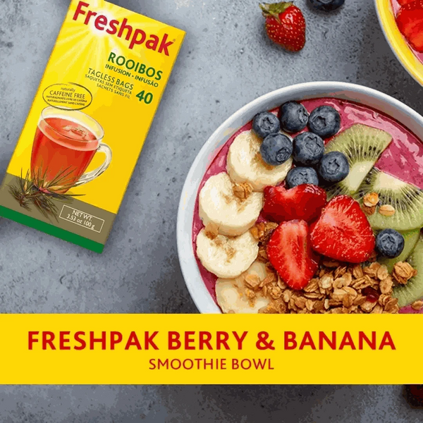 Freshpak Rooibos Tea box next to a berry and banana smoothie bowl with blueberries, strawberries, banana slices, kiwi, and granola on a gray surface