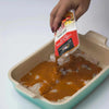 Ina Paarman Peri-Peri Coat & Cook Sauce being poured over chicken in a baking dish.