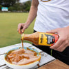 Jan Braai Basting Prego Sauce being poured over raw chicken in a bowl outdoors