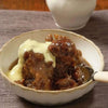 Sticky Malva Pudding with apricot butter glaze served with custard in a bowl.