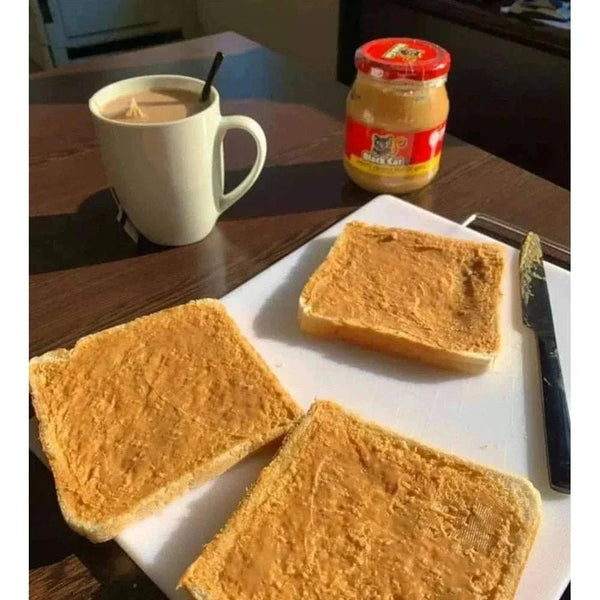Black Cat smooth peanut butter spread on white bread slices with a jar and a mug in the background