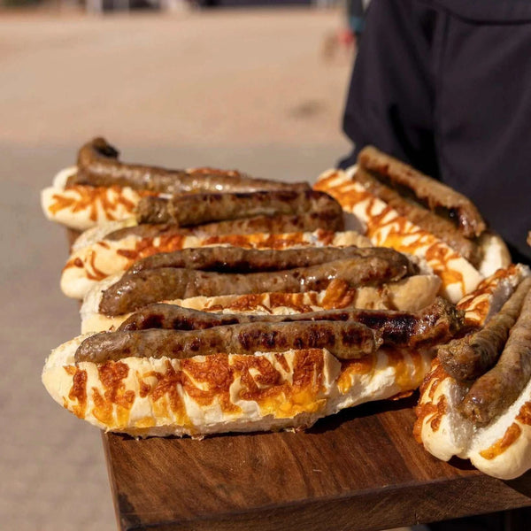 Grilled sausage rolls on cheese-topped bread served on a wooden board, showcasing South African Prego sauce flavor for braai and grilling.
