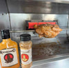 Rooibaard Original Sauce 250ml with rotisserie chicken grilling.