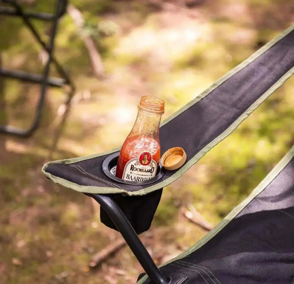 Rooibaard Sauce Baardjang Matige Tamatie bottle on outdoor chair, perfect for grilling and braais.
