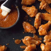 SPUR Durky Sauce on chicken wings with a brush for basting.