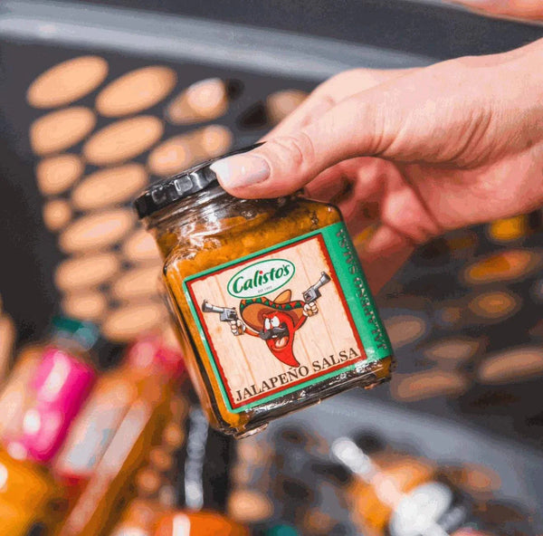 Calisto's Jalapeno Salsa 250ml jar in a hand, showcasing spicy salsa ideal for adding flavor to various dishes.