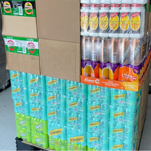 Stack of Schweppes Dry Lemon 300ml cans packaged with other beverage cartons in a warehouse setting