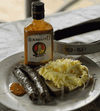 Rooibaard Original Sauce 250ml bottle with sliced sausage and scrambled eggs on a plate.