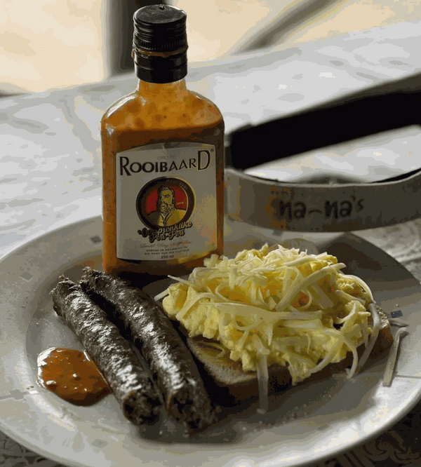 Rooibaard Original Sauce 250ml bottle with sliced sausage and scrambled eggs on a plate.