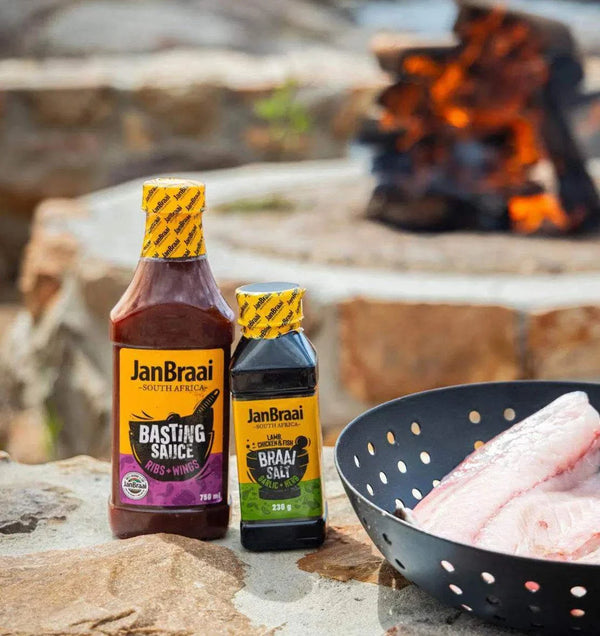Jan Braai Basting Ribs & Wings sauce with fire in background.
