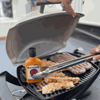 Rooibaard Original Sauce 250ml bottle next to grilling meat on barbecue.