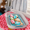 Bakers Zoo Biscuits 150g with iced animal shapes on colorful backgrounds in a white basket.