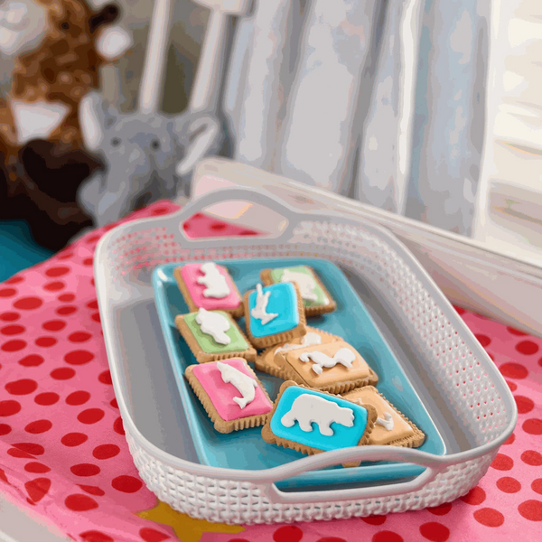 Bakers Zoo Biscuits 150g with iced animal shapes on colorful backgrounds in a white basket.