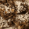Unbaked South African date squares covered in desiccated coconut on a plate