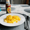 All Gold Tomato Sauce 700ml bottle next to a plate of scrambled eggs on a set dining table.