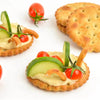 Bakers Salticrax Salted Crackers with hummus, cherry tomatoes, cucumber, and pepper garnishes.