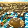Bakers Salticrax Salted Crackers 200g pack on a beach picnic scene with sandals and a straw hat.