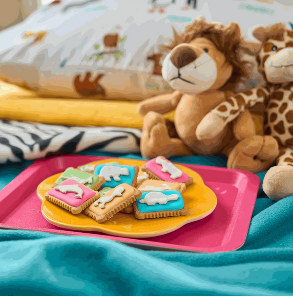Bakers Zoo Biscuits on colorful plate with plush toys in the background.
