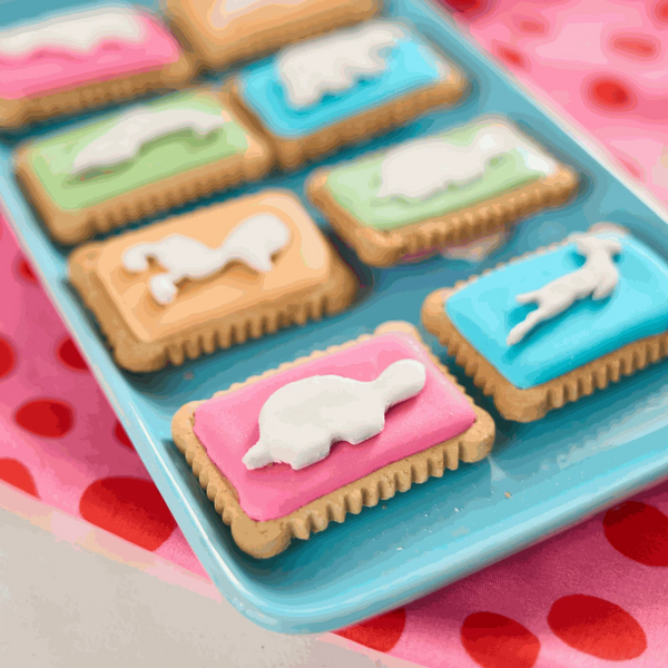 Bakers Zoo Biscuits on a tray with iced animal shapes on colorful backgrounds.