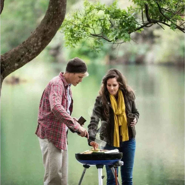 Couple cooking on a CADAC Carri Chef 50 gas BBQ outdoors.