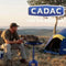 CADAC Skottel Braai in use outdoors near a tent, showcasing versatile outdoor cooking.