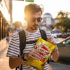 Man holding a bag of Willards Cheese Curls 150g outdoors.