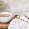 Chocolate Futurelife Zero Smart Food in a white bowl on a wooden surface, next to a striped cloth and a gold spoon.