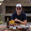 Jan Braai Classic Oxtail Potjie Sauce 400g pouch with cooking ingredients on wooden table outdoors