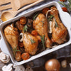 Roasted chicken with garlic and rosemary in a baking dish, featuring fresh rosemary sprigs and cherry tomatoes.