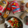 Luckystar Pilchards in Tomato Sauce 400g surrounded by assorted spices and ingredients.