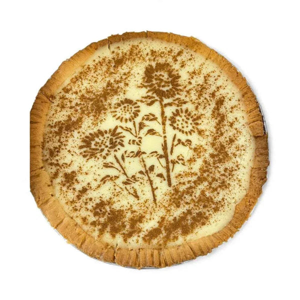 Traditional South African Melktert with cinnamon floral design on creamy custard filling and golden crust