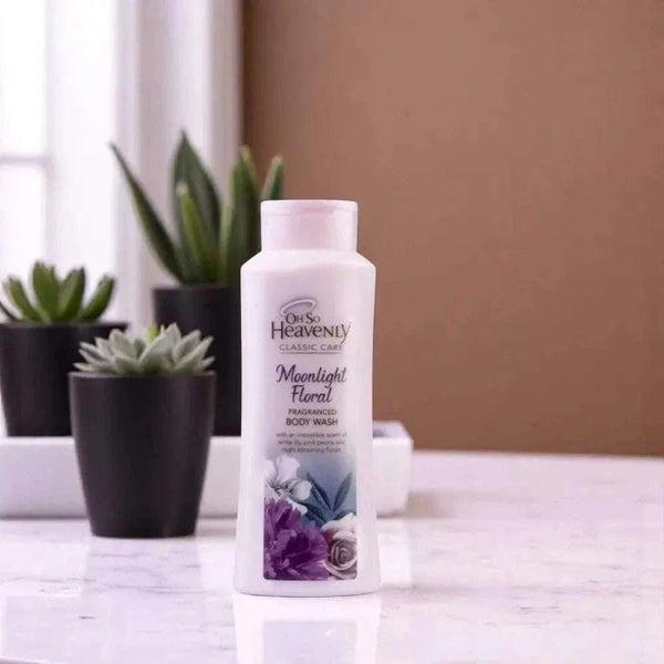 Oh So Heavenly Classic Care Moonlight Floral Body Wash 720ml bottle on a countertop with plants in the background.