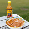 Jan Braai Basting Prego Sauce 750ml bottle with marinated meat in a bowl on wooden table outdoors