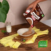 Bokomo ProNutro Chocolate cereal being poured into a bowl on a wooden table with a glass of milk, emphasizing its plant-based protein benefits.