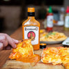 Rooibaard Original Sauce 250ml bottle with pizza slice dipped in sauce.