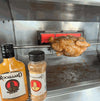 Rooibaard Spice 170ml bottle next to roasting chicken in oven.