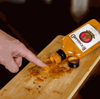 Rooibaard Original Sauce 250ml bottle spilled on wooden board.