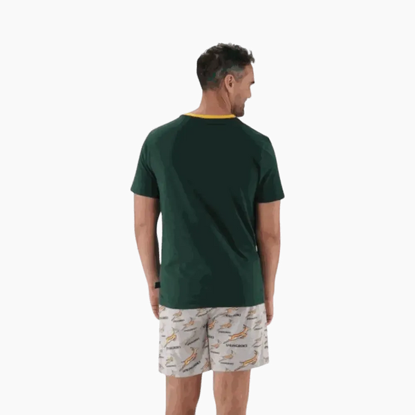 Man wearing 2XL Springbok Pajama Set with green short-sleeve top and white elastic waist shorts with Springbok logo pattern, back view