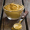 Wimpy Mustard Sauce in a glass bowl with a spoon on wooden surface.